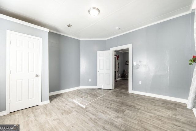 unfurnished bedroom with ornamental molding and light hardwood / wood-style flooring