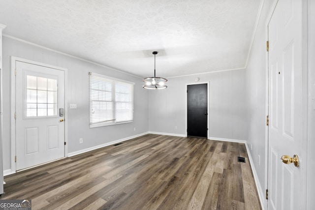 unfurnished dining area with a chandelier, crown molding, dark wood-type flooring, and a textured ceiling