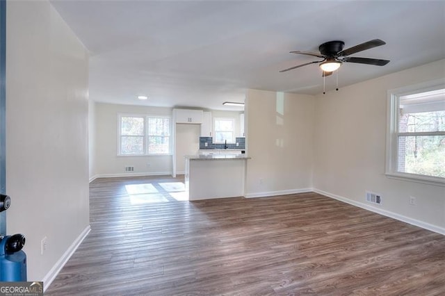 unfurnished living room featuring a wealth of natural light, dark hardwood / wood-style flooring, and ceiling fan