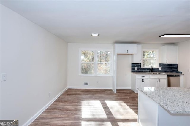 kitchen with dishwasher, light stone counters, white cabinetry, and tasteful backsplash