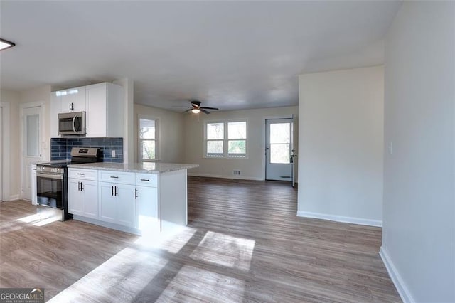 kitchen with backsplash, light stone countertops, white cabinetry, and stainless steel appliances