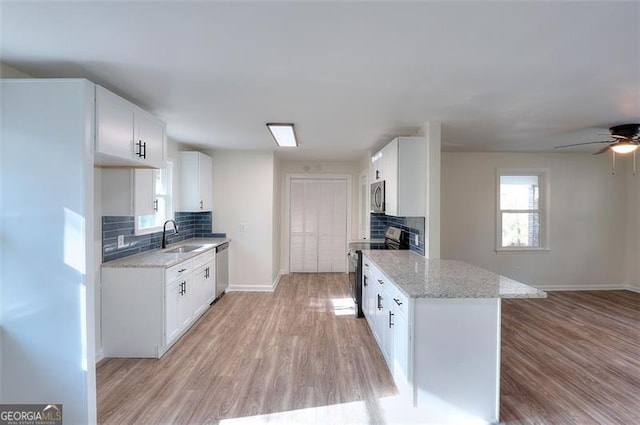 kitchen with backsplash, light stone counters, white cabinetry, and stainless steel appliances