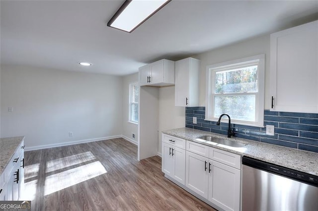 kitchen featuring dishwasher, white cabinetry, light stone countertops, and sink