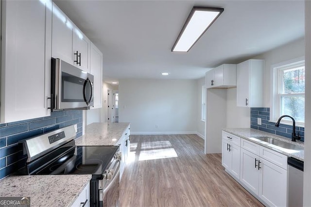 kitchen featuring decorative backsplash, white cabinetry, sink, and stainless steel appliances