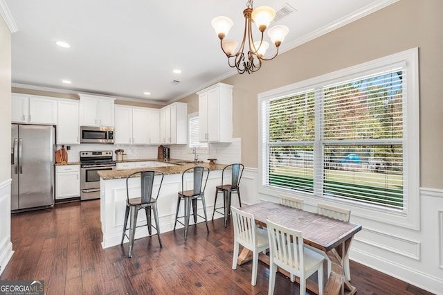 kitchen with white cabinets, dark stone countertops, stainless steel appliances, and hanging light fixtures