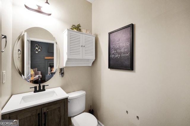 bathroom with vanity, a large fireplace, and toilet