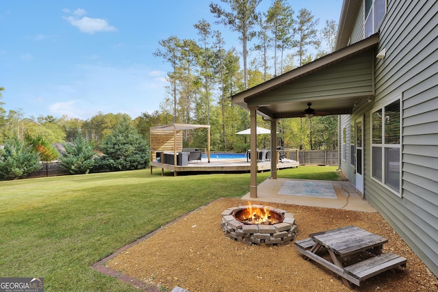 view of yard featuring ceiling fan, a pool side deck, and a fire pit