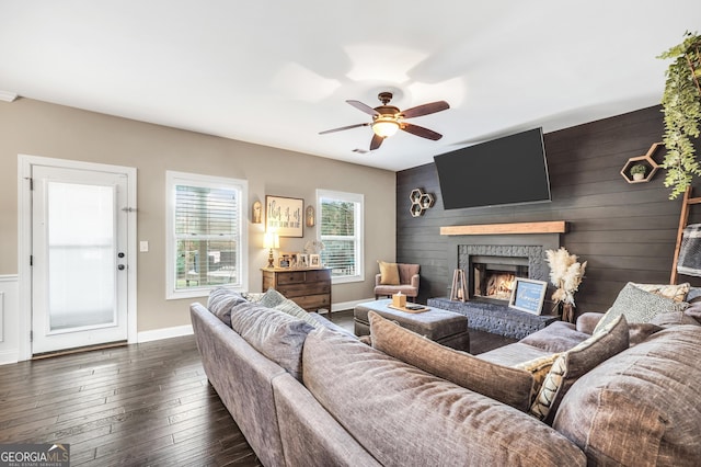 living room with ceiling fan, a fireplace, wood walls, and dark hardwood / wood-style floors