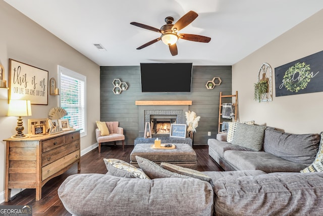 living room featuring wooden walls, a brick fireplace, ceiling fan, and dark wood-type flooring