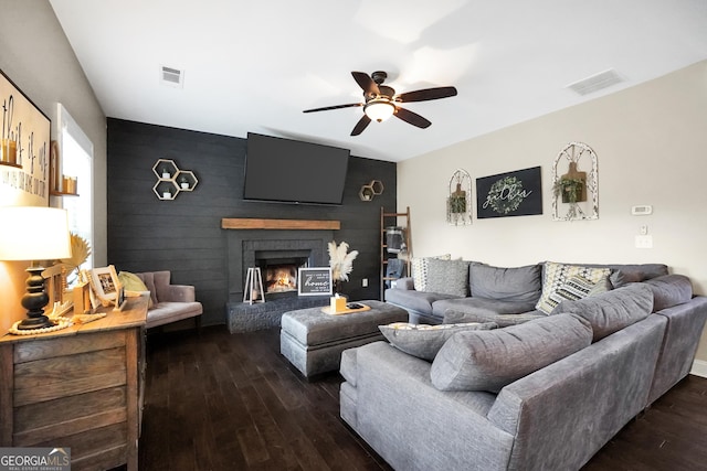 living room featuring ceiling fan, a fireplace, and dark hardwood / wood-style floors