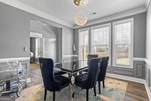 dining room with a wealth of natural light, crown molding, wood-type flooring, and a notable chandelier