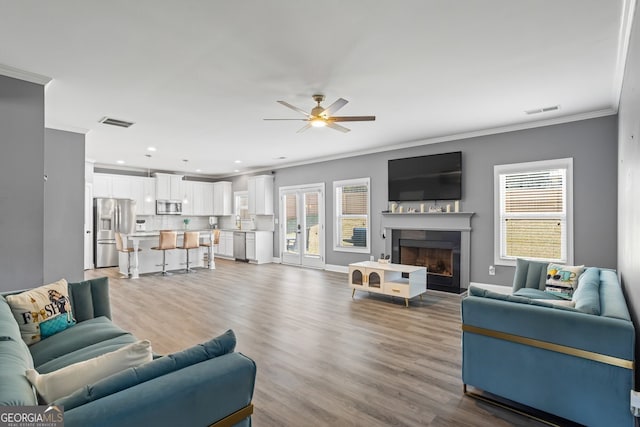 living room with hardwood / wood-style floors, ceiling fan, and ornamental molding