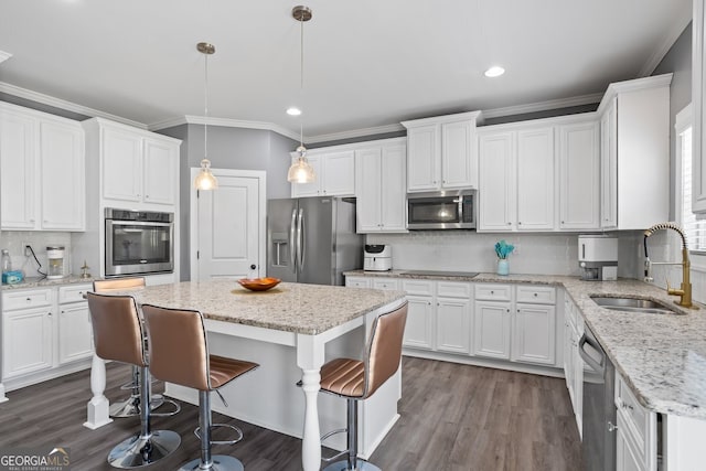 kitchen featuring white cabinets, sink, stainless steel appliances, and hanging light fixtures