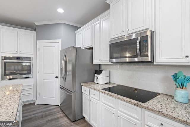 kitchen with light stone countertops, backsplash, crown molding, white cabinets, and appliances with stainless steel finishes