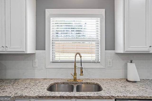 details featuring white cabinetry, light stone counters, and sink