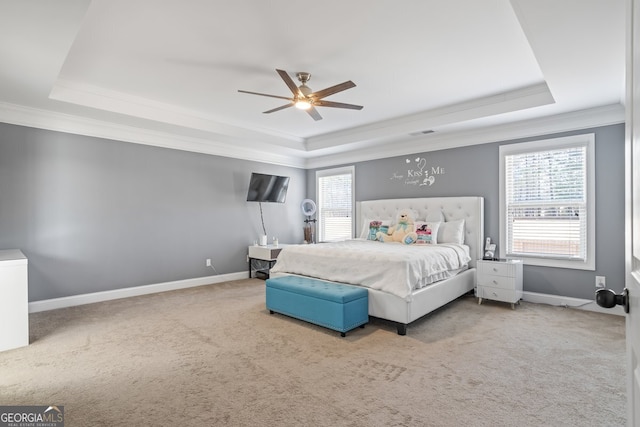 carpeted bedroom featuring a tray ceiling, multiple windows, and ceiling fan