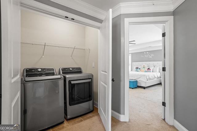 washroom featuring washing machine and dryer, light colored carpet, and ornamental molding