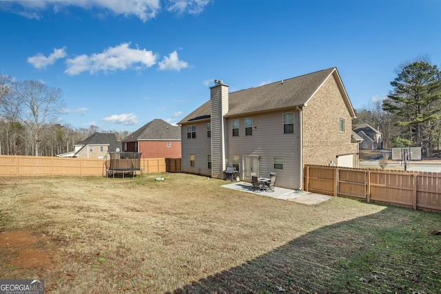 back of property featuring a yard, a patio, and a trampoline