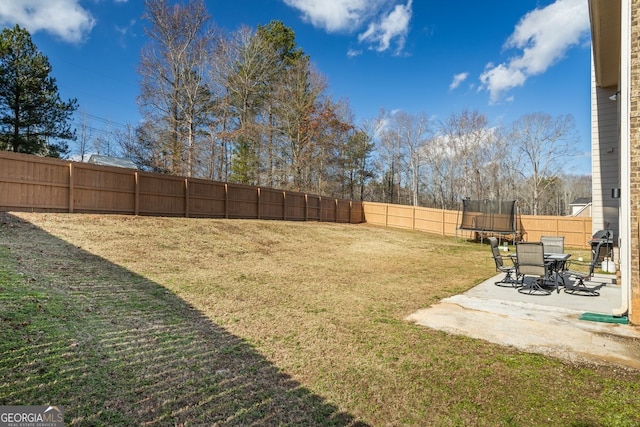 view of yard with a trampoline and a patio area