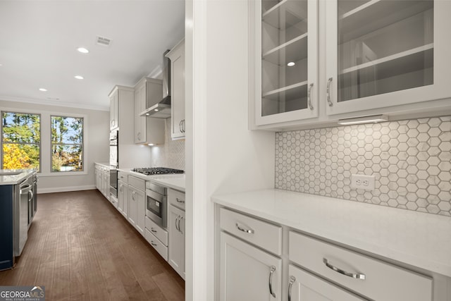 kitchen featuring stainless steel gas cooktop, white cabinetry, crown molding, light stone counters, and decorative backsplash