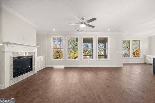 unfurnished living room featuring crown molding, ceiling fan, a high end fireplace, and dark wood-type flooring