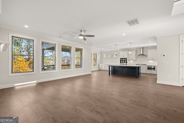 unfurnished living room with ornamental molding, dark wood-type flooring, and ceiling fan