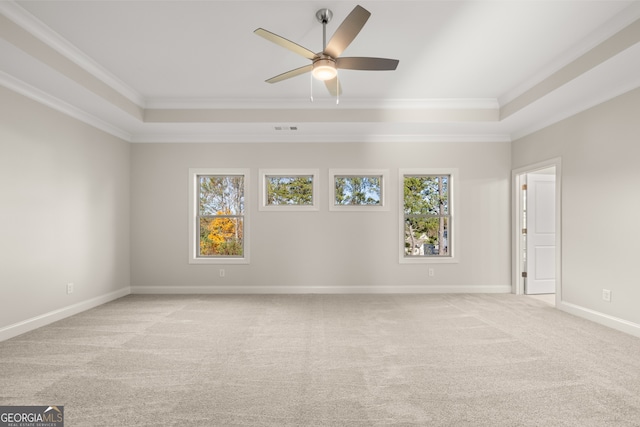 unfurnished room with a raised ceiling, ornamental molding, light colored carpet, and ceiling fan