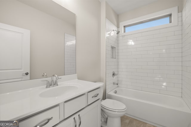 full bathroom featuring tiled shower / bath combo, vanity, wood-type flooring, and toilet