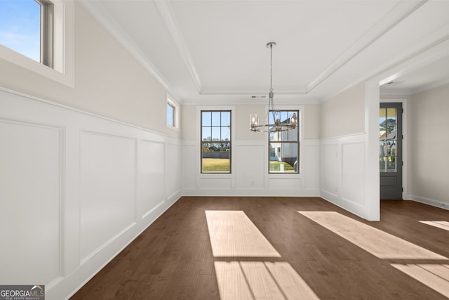 unfurnished dining area with crown molding, dark hardwood / wood-style flooring, a raised ceiling, and a notable chandelier