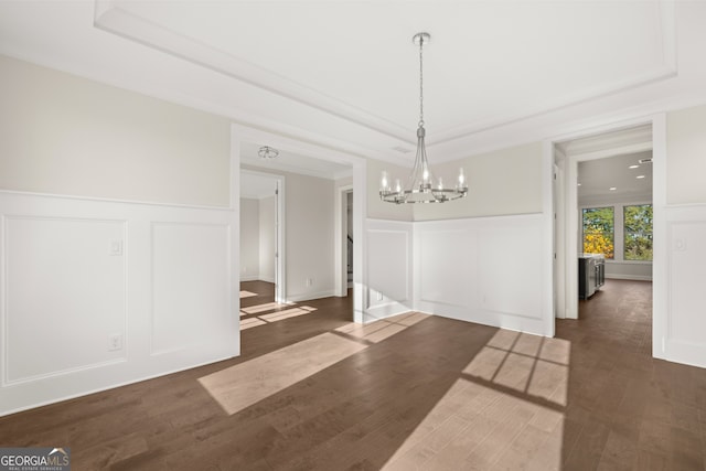 unfurnished dining area with a tray ceiling, dark hardwood / wood-style floors, and a notable chandelier