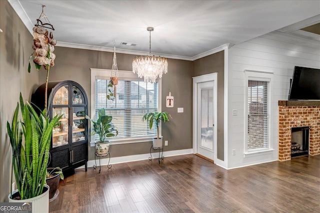 unfurnished dining area featuring dark wood-type flooring, ornamental molding, and a brick fireplace