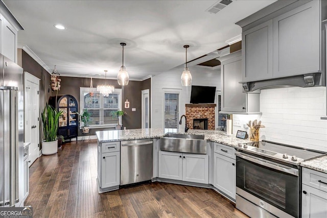 kitchen with hanging light fixtures, a fireplace, sink, and appliances with stainless steel finishes