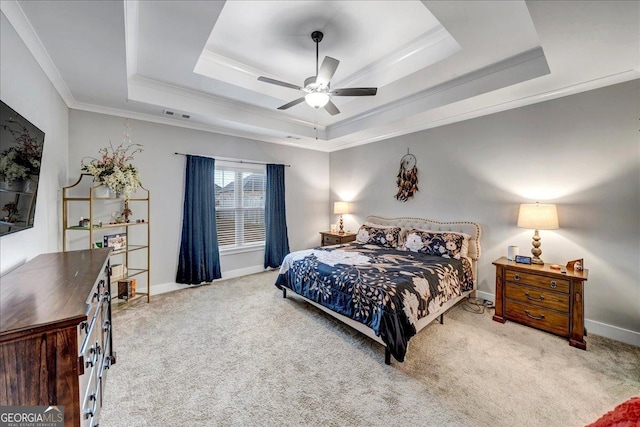 bedroom featuring a tray ceiling, ceiling fan, crown molding, and light carpet