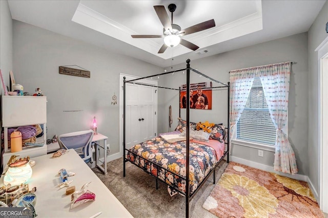 carpeted bedroom featuring ceiling fan, a raised ceiling, and crown molding