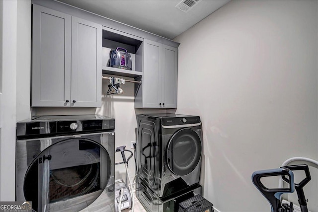 clothes washing area with cabinets and separate washer and dryer