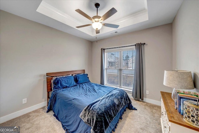 carpeted bedroom featuring ceiling fan and a raised ceiling