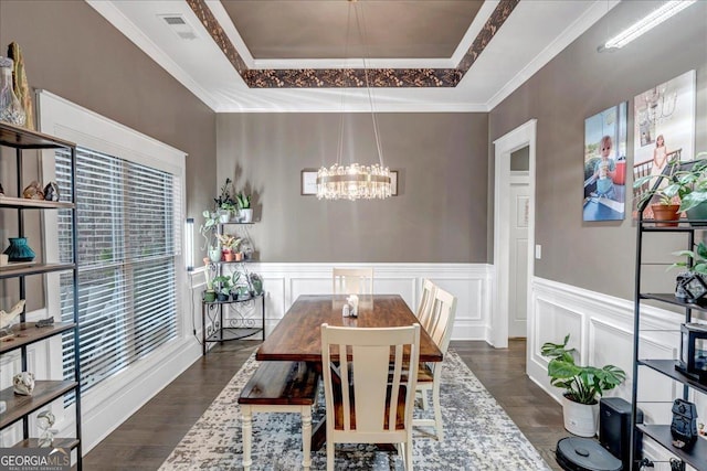 dining room featuring a tray ceiling, crown molding, dark wood-type flooring, and a notable chandelier