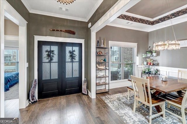 entryway featuring crown molding, french doors, dark wood-type flooring, and an inviting chandelier