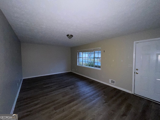 spare room with dark wood-type flooring and a textured ceiling