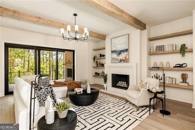 living room featuring a notable chandelier, beam ceiling, light wood-type flooring, and built in features