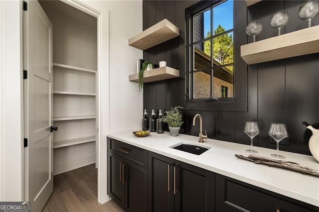 bar featuring dark brown cabinetry, wood-type flooring, and sink