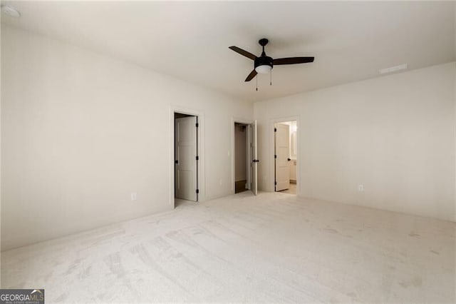 unfurnished bedroom featuring connected bathroom, ceiling fan, and light colored carpet