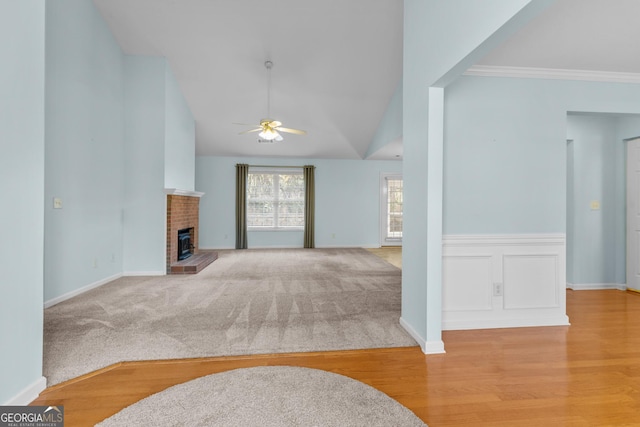 living room featuring ceiling fan, crown molding, lofted ceiling, a fireplace, and light wood-type flooring