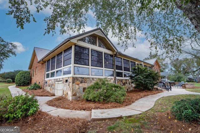 exterior space with stone siding, a sunroom, and metal roof