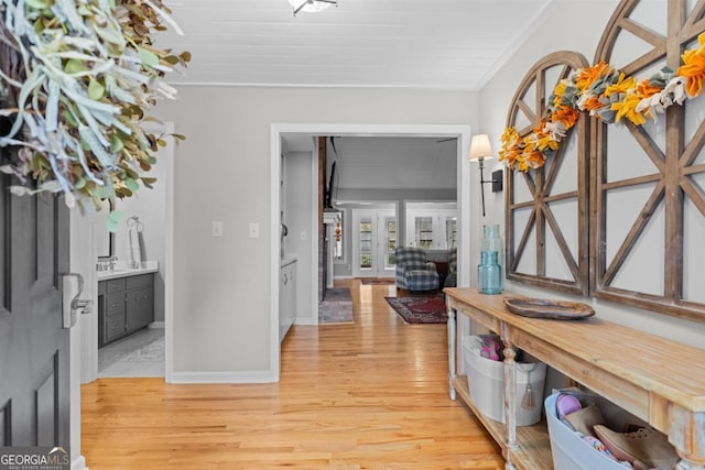 foyer entrance featuring ornamental molding, light wood-style flooring, and baseboards