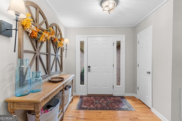 entryway featuring crown molding, light wood-style flooring, and baseboards