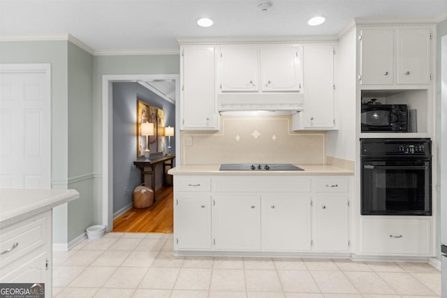 kitchen featuring under cabinet range hood, white cabinets, light countertops, ornamental molding, and black appliances