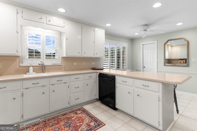 kitchen featuring light countertops, decorative backsplash, white cabinets, a sink, and a peninsula