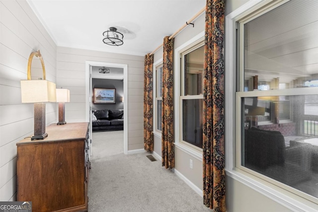 hall with light colored carpet, visible vents, and baseboards