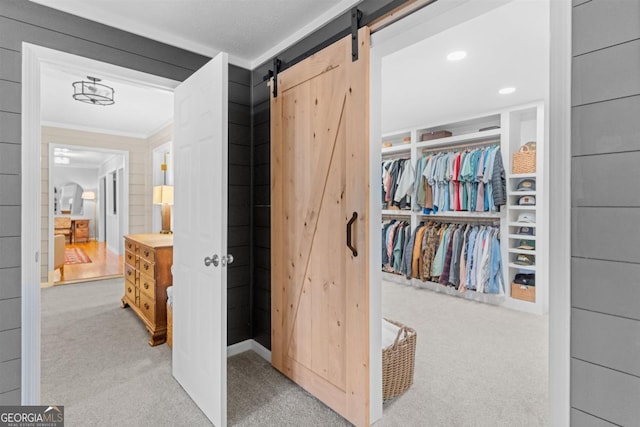 corridor with light carpet, a barn door, ornamental molding, and recessed lighting